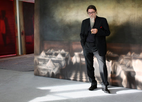 Portrait von Nikolai Makarov im Studio vor einem Bild der Paris Bar und den roten Portraits im Hintergrund